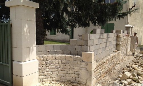 Création d'un mur de clôture en pierre , pose de pilier en pierre . 